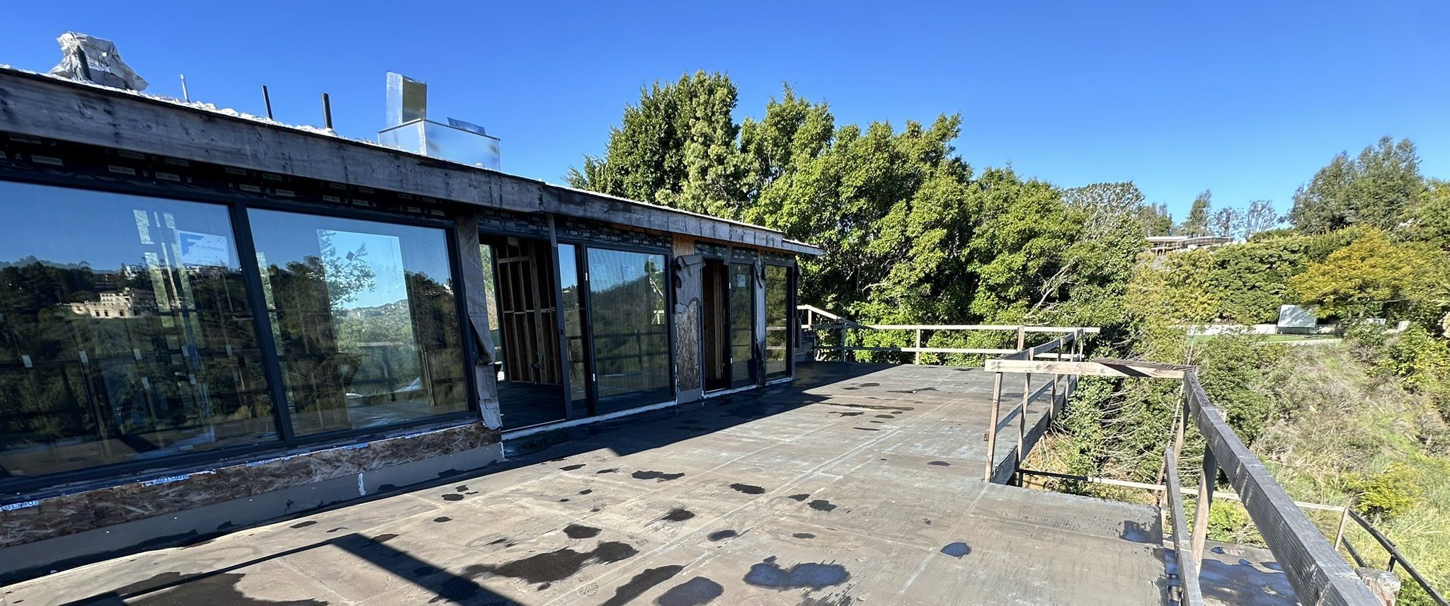 The upper deck and tall windows of the Akopi Builders hillside custom home in Bel Air, under construction, with the canyon beyond