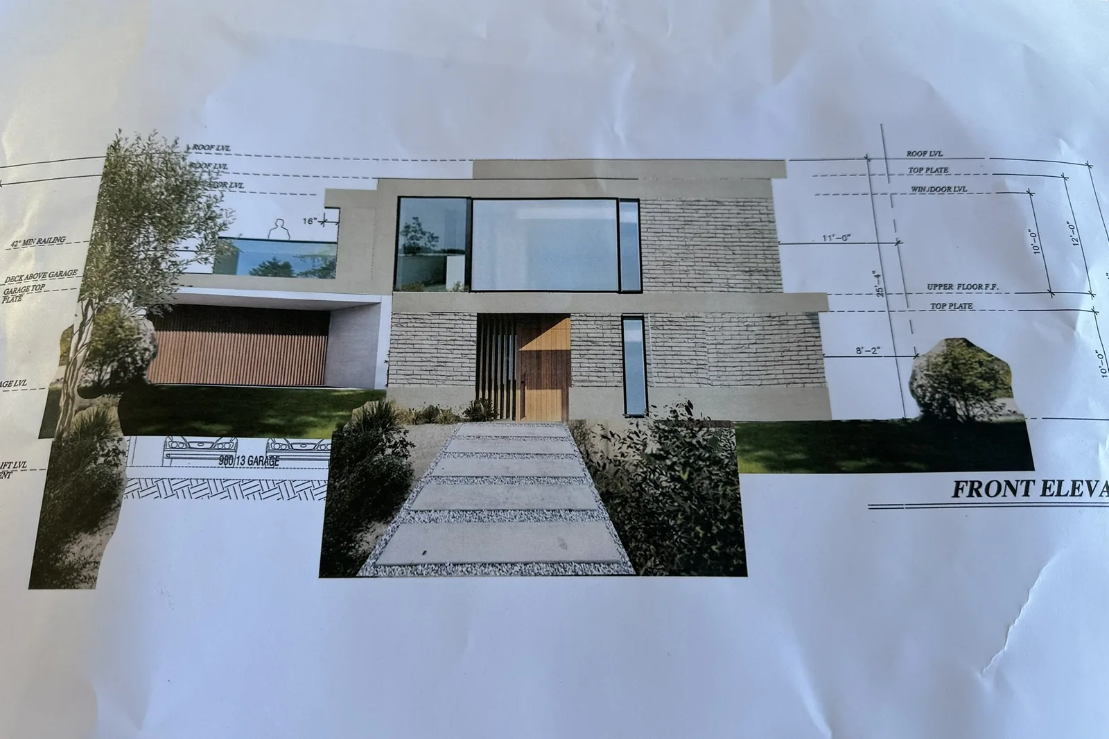 A printed front elevation drawing of a modern two-story house with stucco, stone veneer and large windows, for an Akopi Builders custom home in Bel Air.