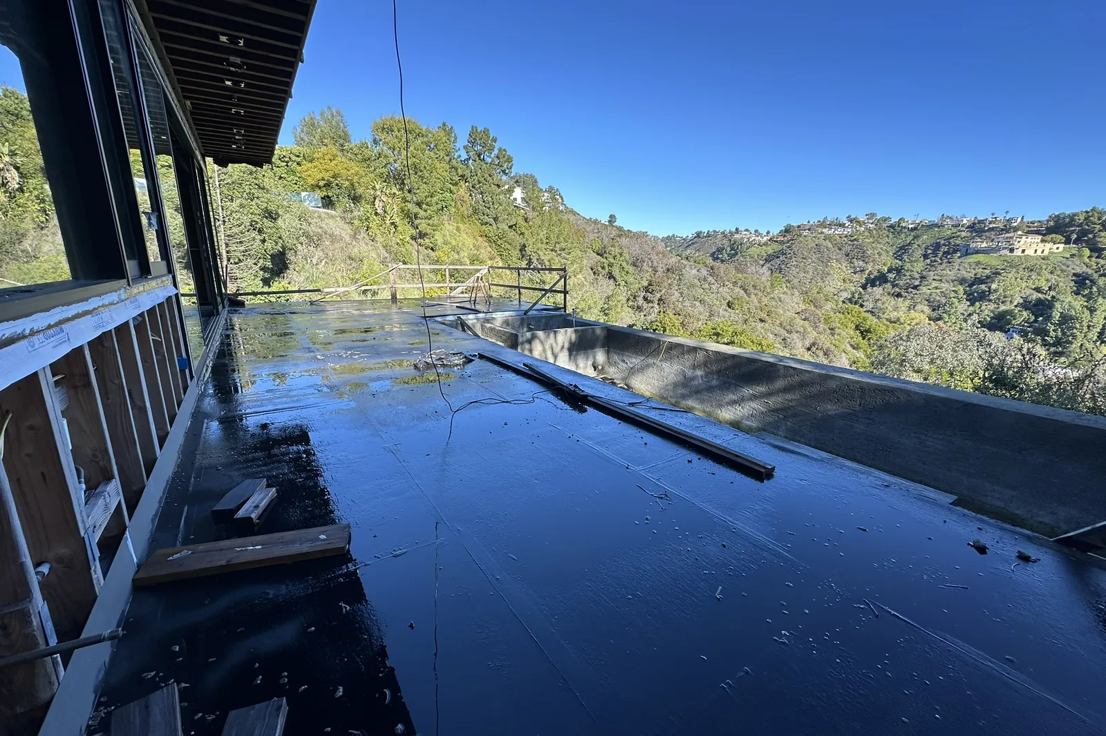 A hillside deck being waterproofed on an Akopi Builders project in Bel Air, with the houses across the canyon in view.