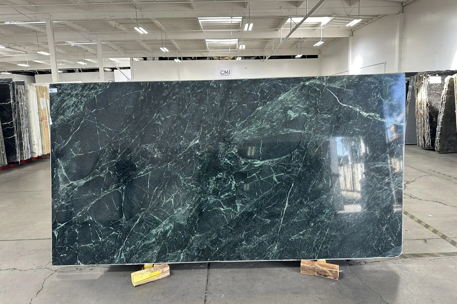 A polished green marble slab with white veining at a stone yard, seen during an Akopi Builders custom home build in Bel Air.