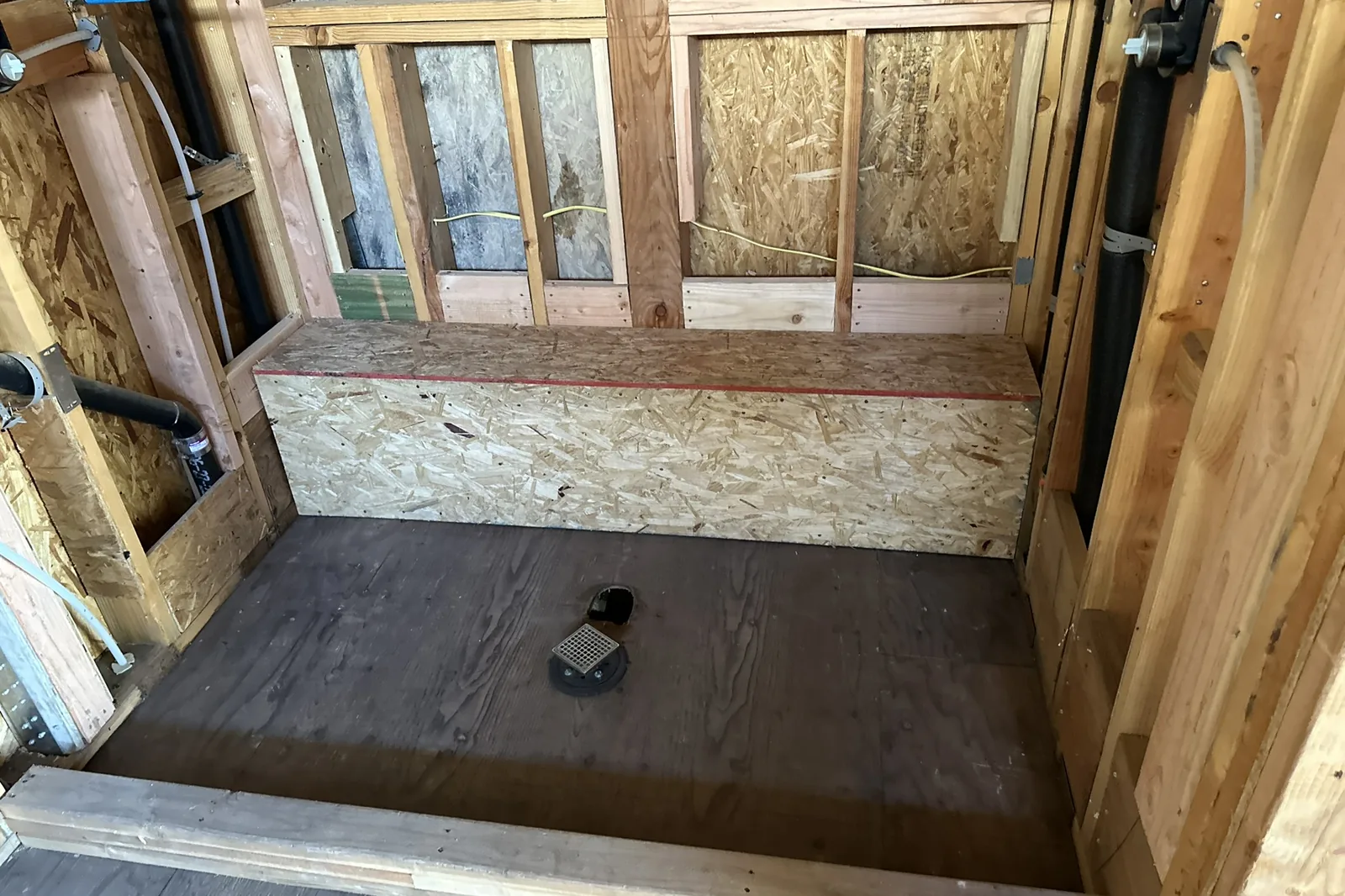 A framed shower with a bench and a center drain before waterproofing and tile, in an Akopi Builders custom home in Bel Air.