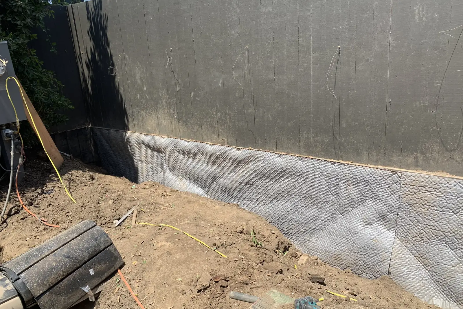 A retaining wall with a dimpled drainage and waterproofing membrane along its base before backfill, on an Akopi Builders project in Santa Monica.