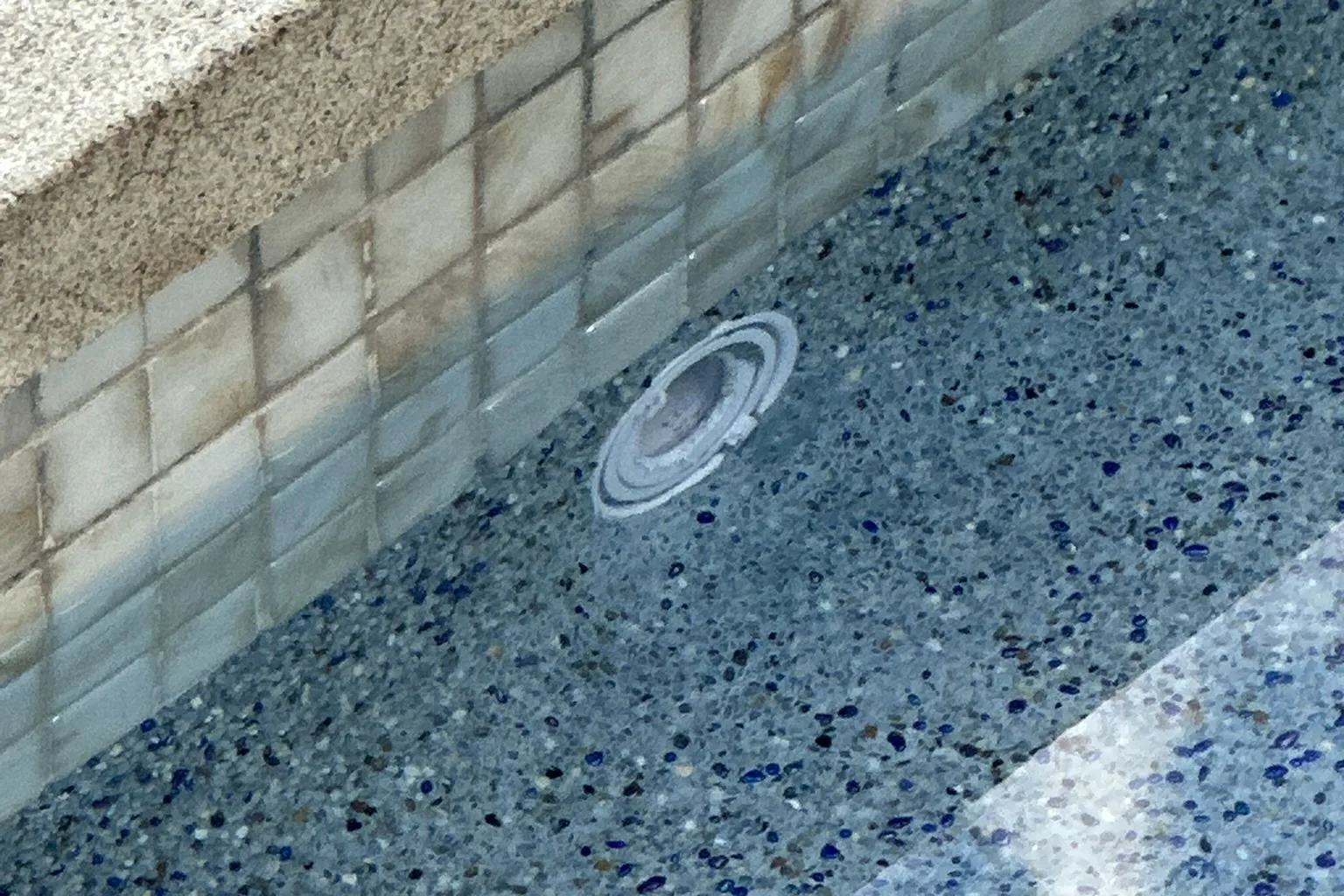Close-up of a glass tile waterline band, coping edge and blue pebble interior finish in the Arnwood pool, an Akopi Builders build in Los Angeles.