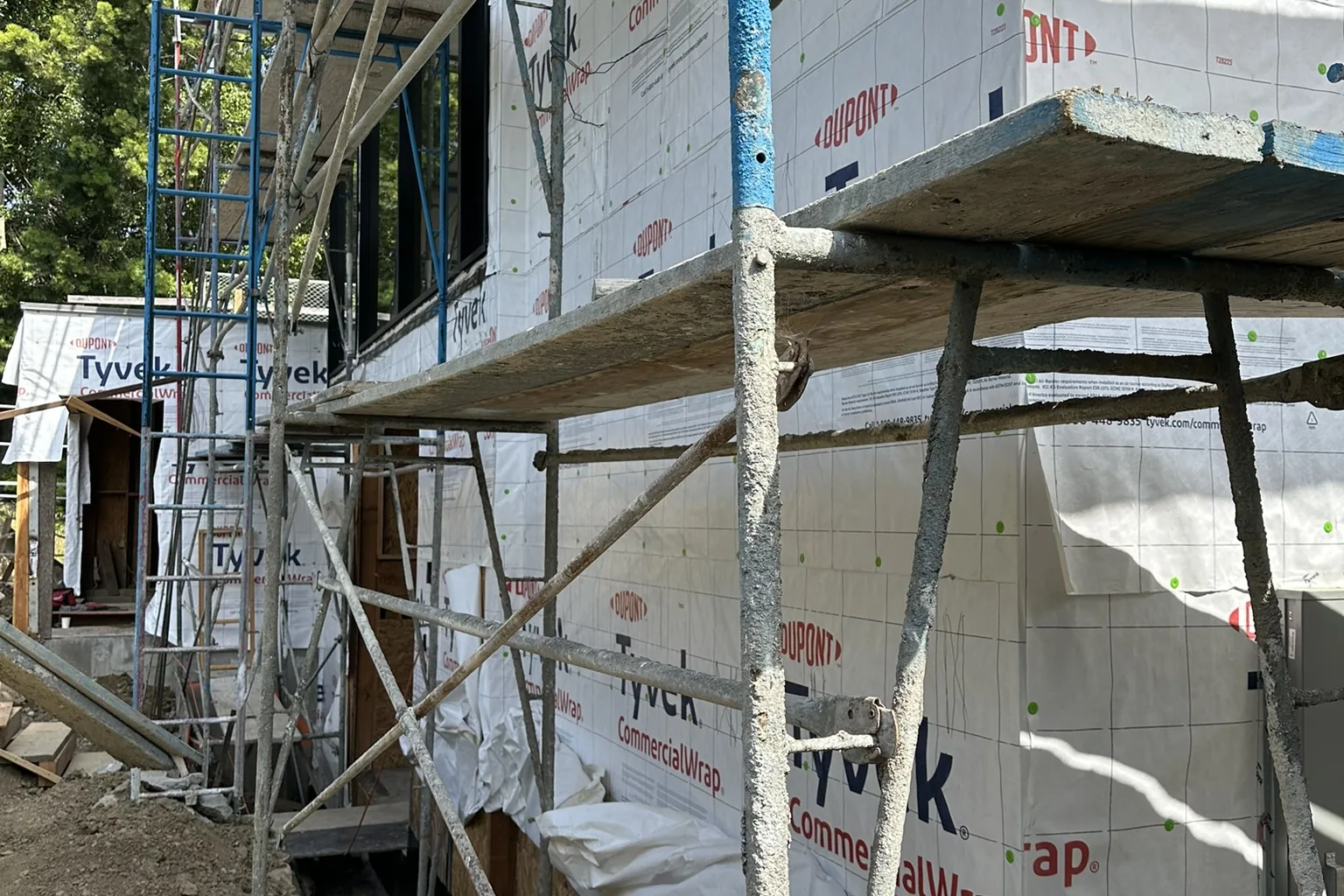 A hillside custom home under construction in Bel Air by Akopi Builders, with house wrap and scaffolding; it is not a Palisades rebuild.