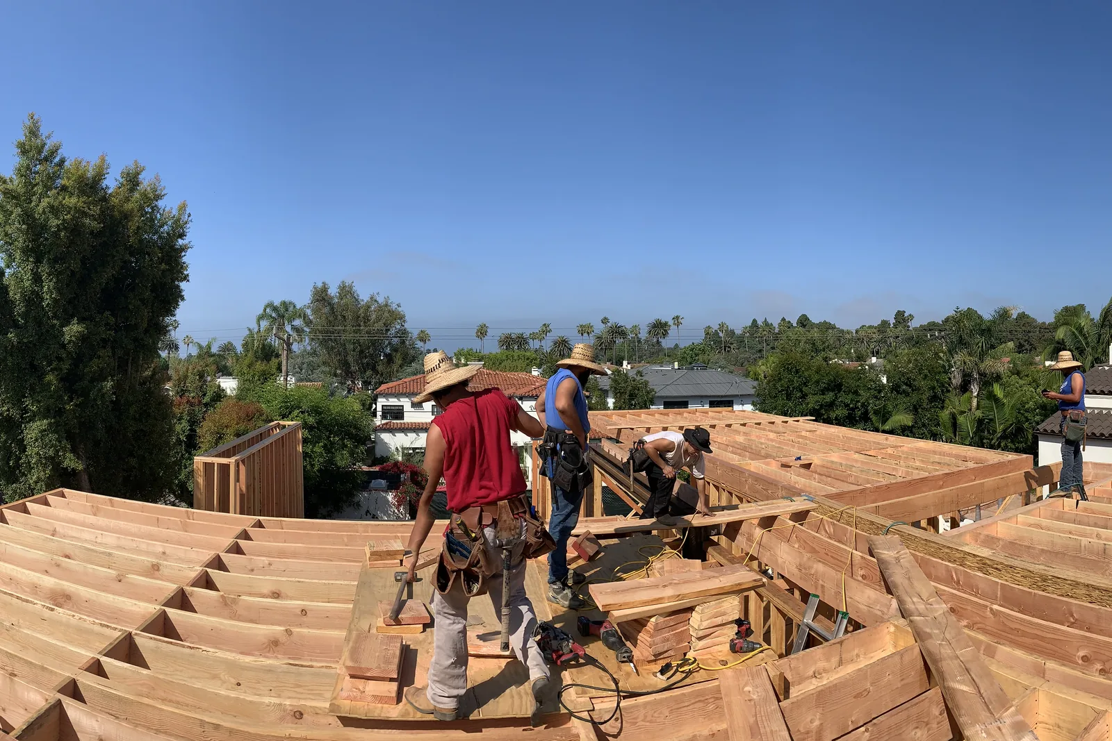 Framers working on open roof framing on an Akopi Builders project in Santa Monica, before the roof is sheathed.