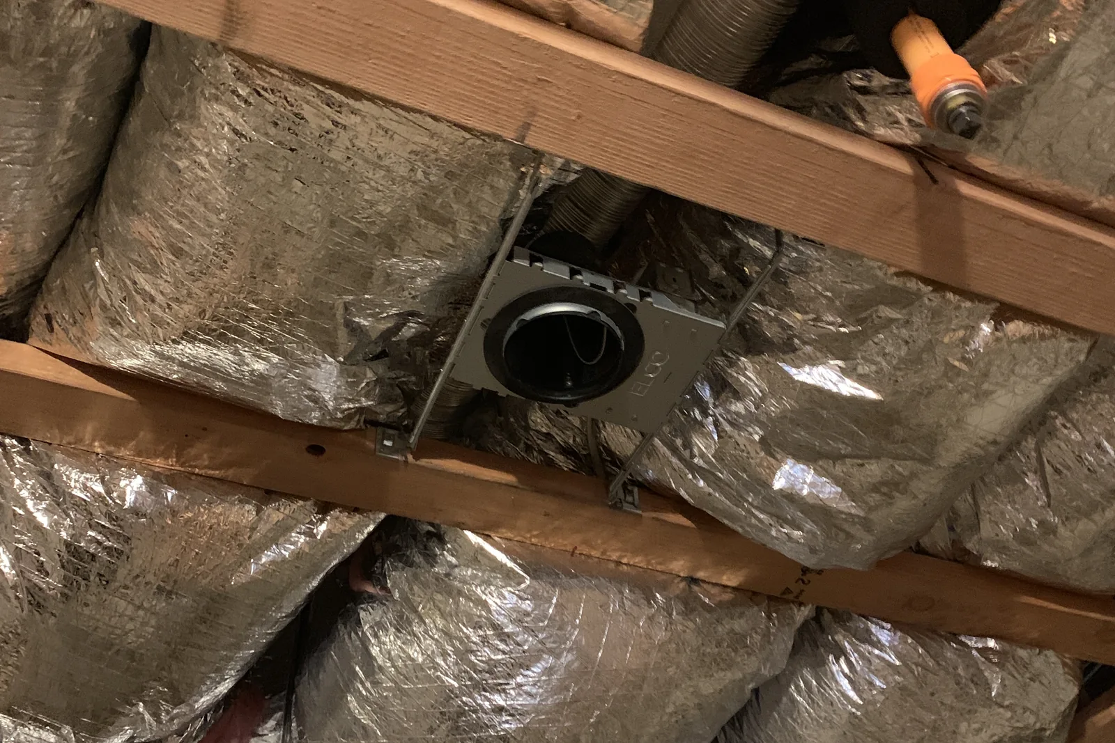 Foil-wrapped ducts and a ceiling fan housing between joists on an Akopi Builders project in Santa Monica.
